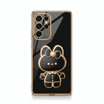 Samsung Galaxy phone case with a glossy black mirror finish, gold trim, and a raised bear character stand