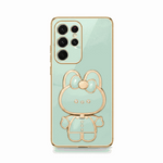 Samsung Galaxy phone case in mint green with gold trim and glossy finish, featuring a raised bunny character stand